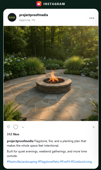 Burning stone fire pit on a circular flagstone patio surrounded by lush garden greenery.